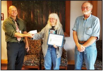 Chris Cooper (L) Director of Library Services, accepts a check for $2,000 from Kay Belschner, recipient of the 2022 Frances Rapin Community Service Award. Kay and the Library Staff will decide how the money will be used. James Cech (R), President of FRL, explained how much Kay has done for the Library and the Friends, and presented her with a certificate and the check for the Library.